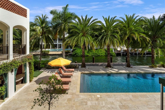 view of swimming pool featuring a water view and a patio