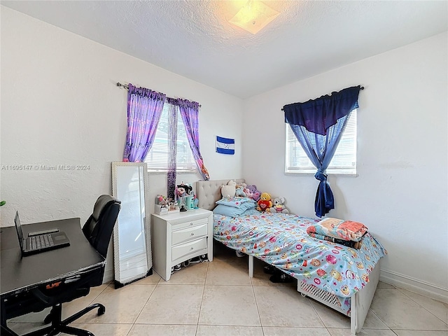 tiled bedroom with a textured ceiling and multiple windows