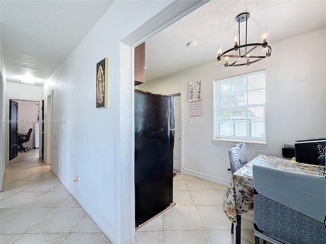 kitchen with black refrigerator, light tile patterned floors, hanging light fixtures, and a chandelier