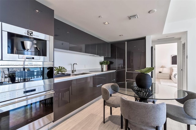 kitchen with black cooktop, sink, and light wood-type flooring