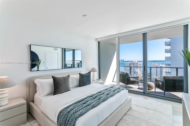 bedroom with expansive windows, a water view, access to outside, and light hardwood / wood-style flooring