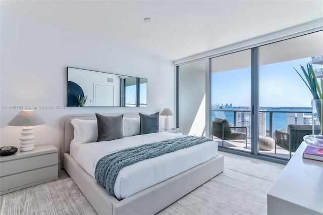 carpeted bedroom with access to exterior, a water view, and expansive windows