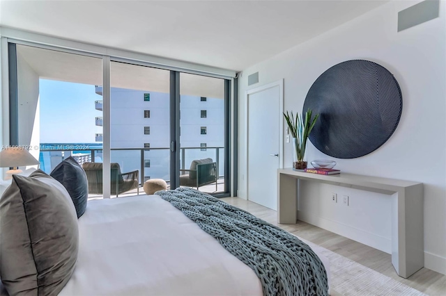 bedroom with light hardwood / wood-style floors and a wall of windows