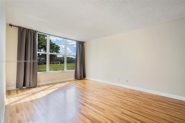 unfurnished room with a textured ceiling and light hardwood / wood-style flooring