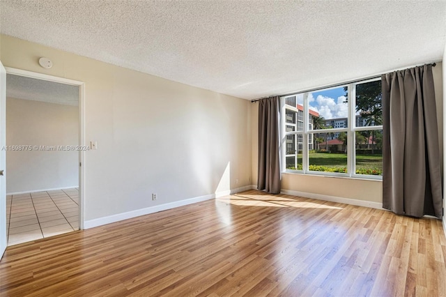 empty room featuring light wood-type flooring and a textured ceiling