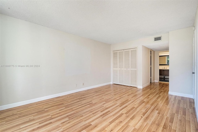 unfurnished room featuring a textured ceiling and light hardwood / wood-style floors