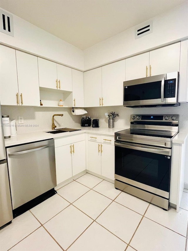 kitchen featuring white cabinets, light tile patterned floors, stainless steel appliances, and sink