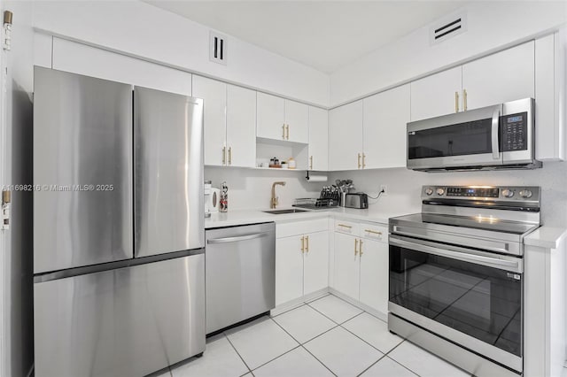 5700 Collins Ave Unit 5B, Miami Beach, FL 33140 - kitchen with stainless steel appliances, light countertops, white cabinets, open shelves, and light tile patterned floors