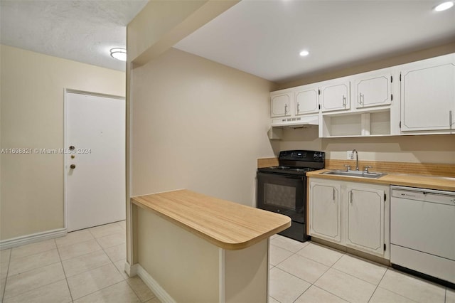 kitchen featuring dishwasher, sink, black electric range, light tile patterned floors, and white cabinetry