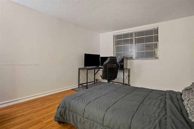 bedroom with a textured ceiling and hardwood / wood-style flooring