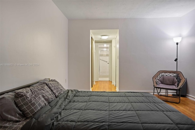 bedroom with ensuite bathroom and light hardwood / wood-style flooring