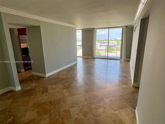 spare room with floor to ceiling windows, crown molding, and baseboards