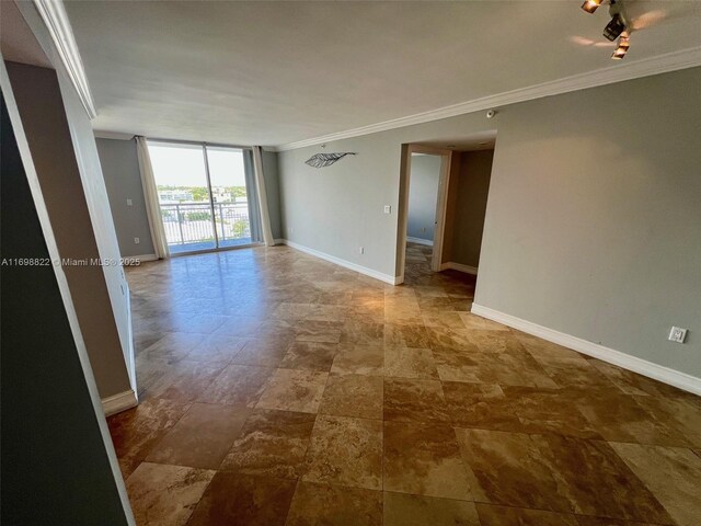 spare room featuring track lighting, crown molding, and baseboards