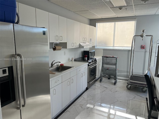 kitchen with marble finish floor, stainless steel appliances, light countertops, a sink, and under cabinet range hood