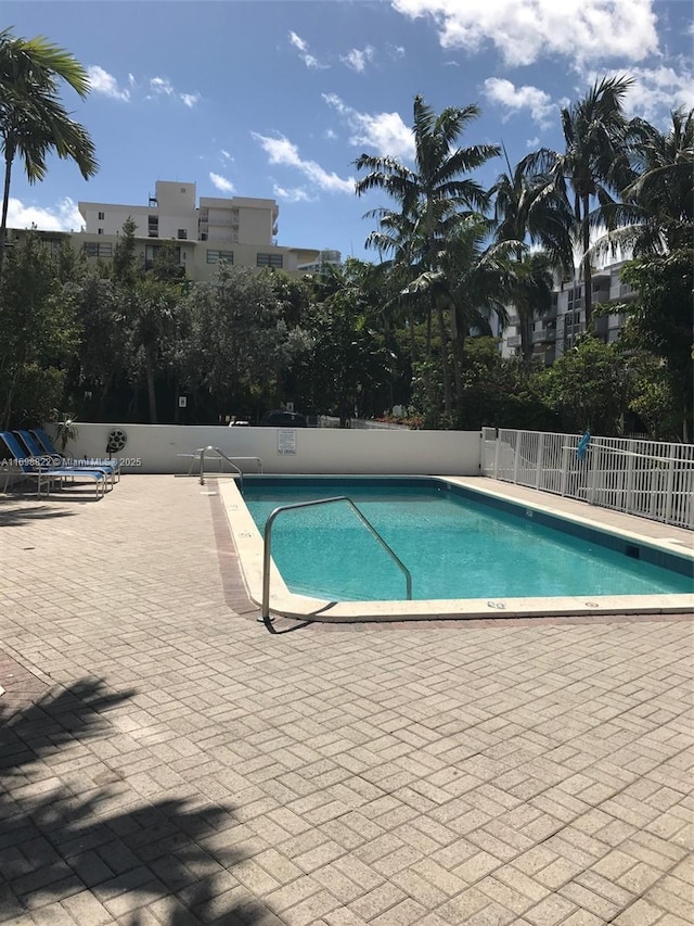 pool with a patio area and fence