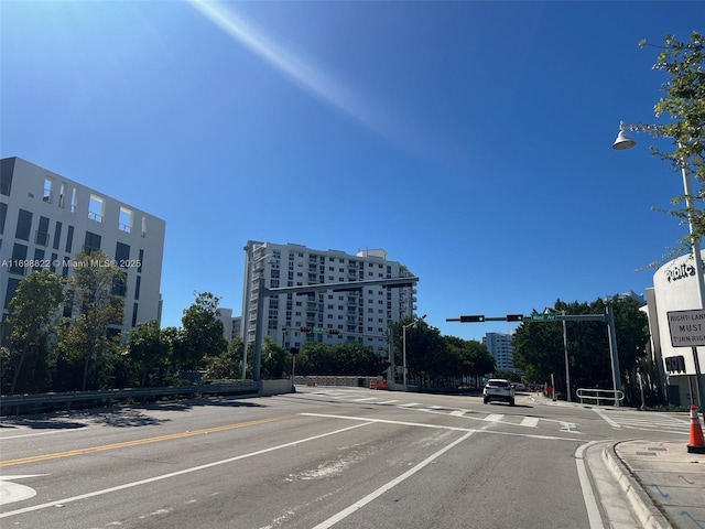 view of road featuring sidewalks, traffic lights, street lights, and curbs