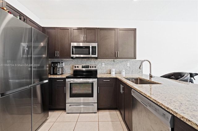 kitchen with sink, light stone counters, backsplash, light tile patterned floors, and appliances with stainless steel finishes