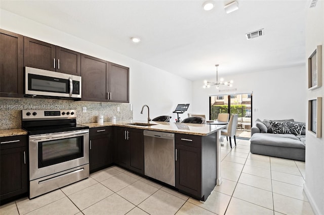 kitchen with kitchen peninsula, appliances with stainless steel finishes, dark brown cabinetry, sink, and a chandelier