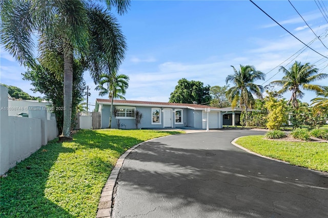 ranch-style house featuring an attached garage, fence, driveway, stucco siding, and a front lawn