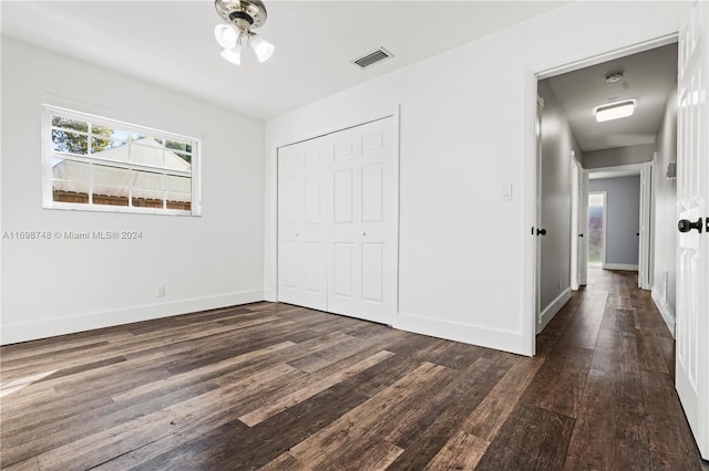 unfurnished bedroom with dark wood-type flooring and a closet