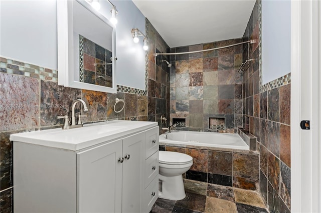 full bathroom featuring vanity, toilet, tiled shower / bath, and tile walls