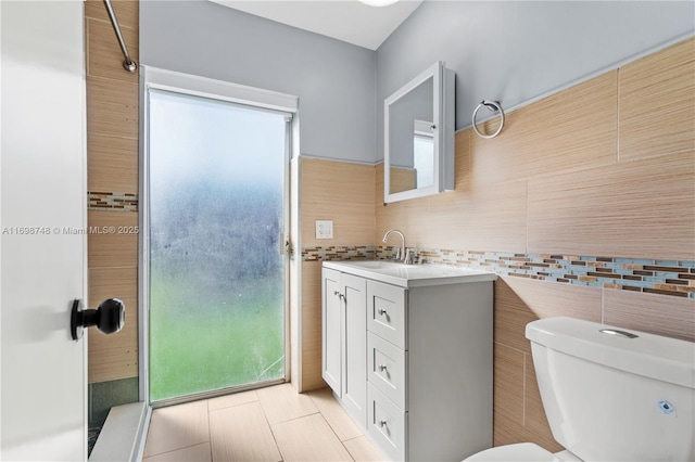 bathroom featuring vanity, toilet, and tile walls