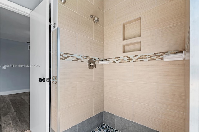 bathroom with a tile shower and wood finished floors