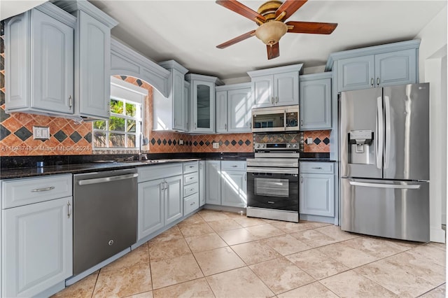 kitchen with backsplash, dark stone countertops, ceiling fan, and appliances with stainless steel finishes