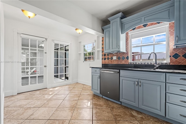 kitchen with dishwasher, sink, blue cabinetry, tasteful backsplash, and light tile patterned flooring