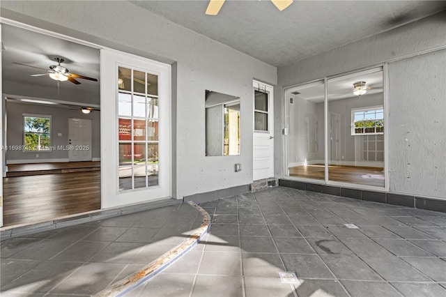 interior space with ceiling fan, baseboards, a wealth of natural light, and tile patterned floors