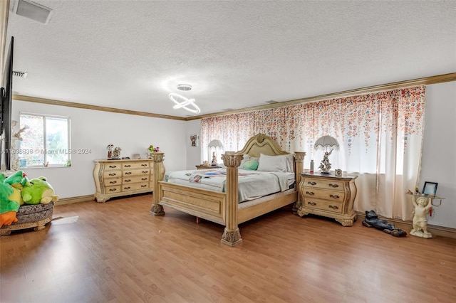 bedroom with ornamental molding, a textured ceiling, and hardwood / wood-style flooring