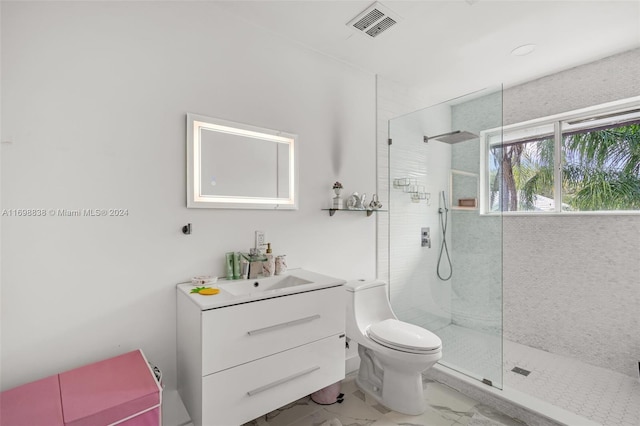 bathroom with vanity, toilet, and tiled shower