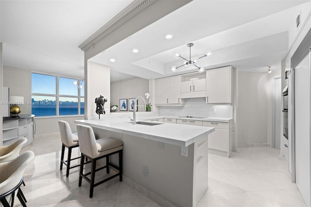 kitchen with sink, a water view, a kitchen bar, black electric stovetop, and white cabinets