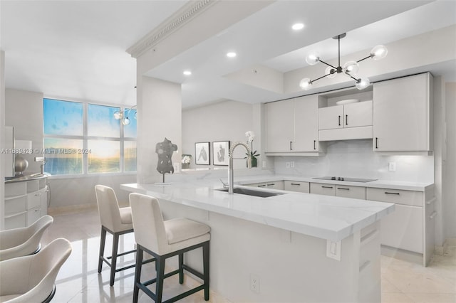 kitchen with white cabinetry, sink, black electric stovetop, kitchen peninsula, and a breakfast bar