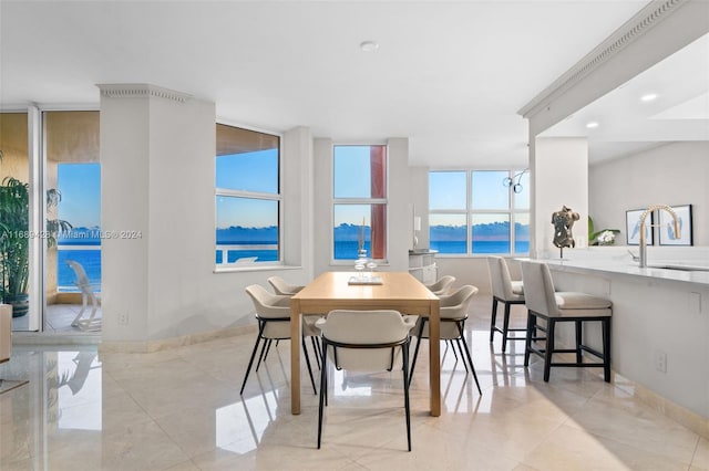 dining room featuring floor to ceiling windows, sink, a water view, and a healthy amount of sunlight