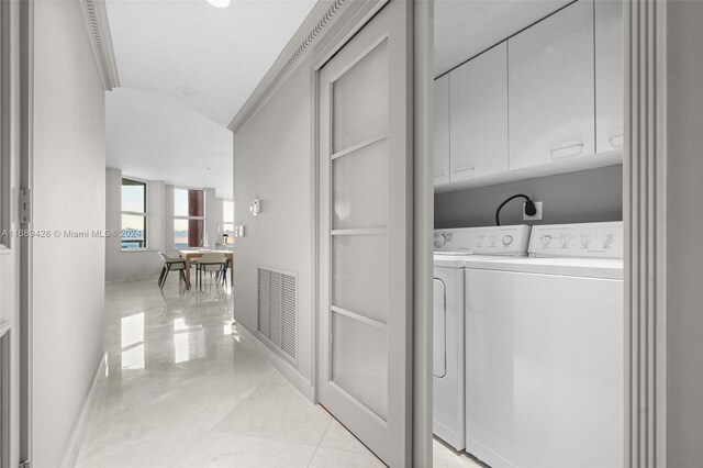 laundry room featuring washer and dryer, cabinets, light tile patterned floors, and crown molding