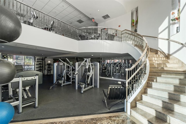 exercise room featuring a towering ceiling