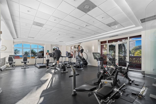 workout area featuring a tray ceiling, a paneled ceiling, and french doors