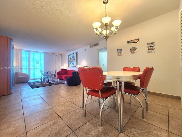 dining room with a textured ceiling, tile patterned floors, a wall of windows, and a notable chandelier