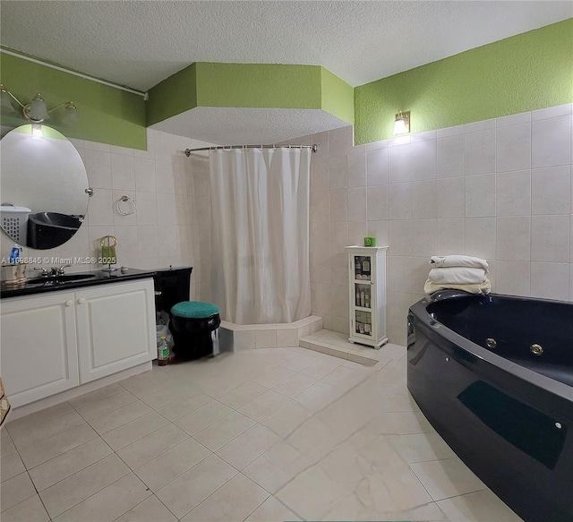 bathroom featuring a tile shower, vanity, a textured ceiling, a jetted tub, and tile walls