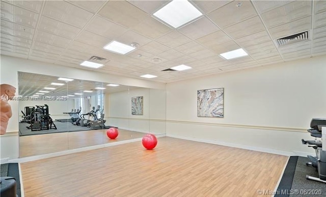 exercise area featuring hardwood / wood-style floors and a drop ceiling