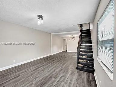 empty room with dark hardwood / wood-style flooring and a textured ceiling