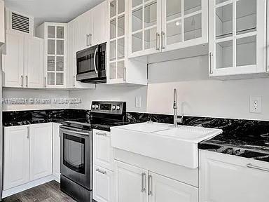 kitchen with white cabinetry, dark wood-type flooring, stainless steel appliances, and sink