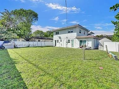 back of house with a yard and a shed