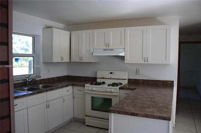 kitchen with white cabinets, white gas stove, light tile patterned flooring, and sink