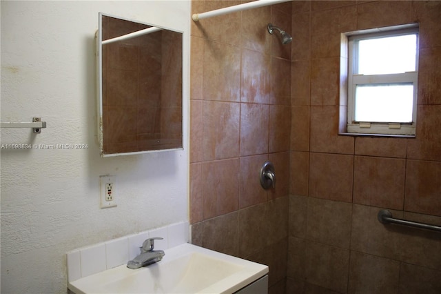 bathroom featuring tiled shower and vanity