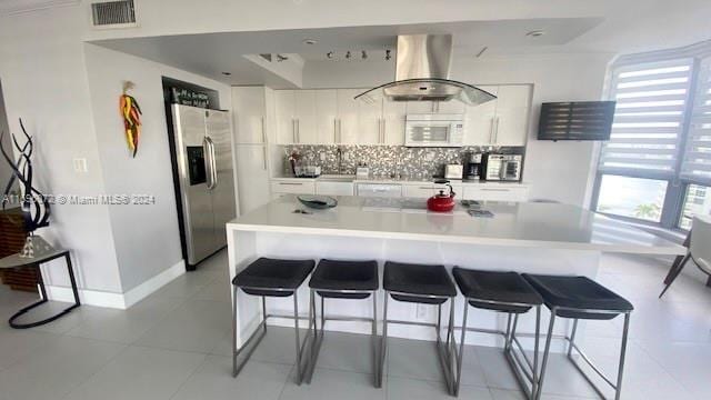 kitchen with decorative backsplash, stainless steel fridge, white cabinets, and a healthy amount of sunlight