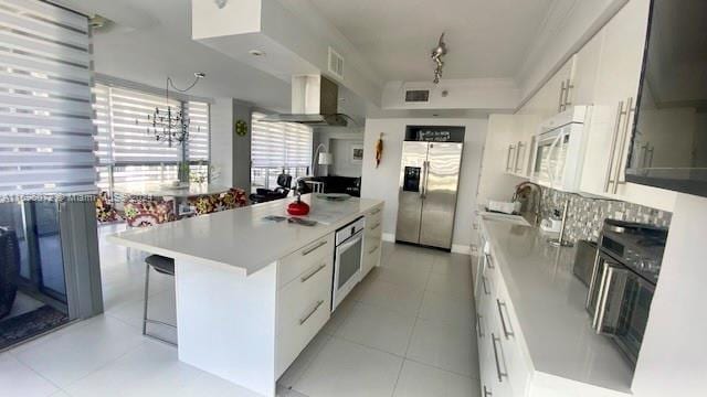 kitchen with white cabinets, oven, wall chimney range hood, and stainless steel refrigerator with ice dispenser