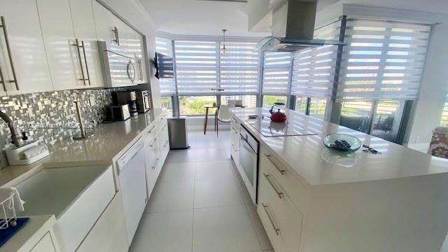 kitchen with tasteful backsplash, white cabinetry, plenty of natural light, and white appliances