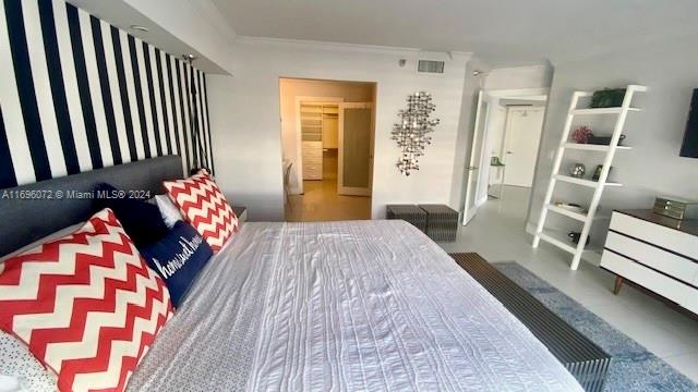 bedroom featuring a spacious closet, a closet, and crown molding